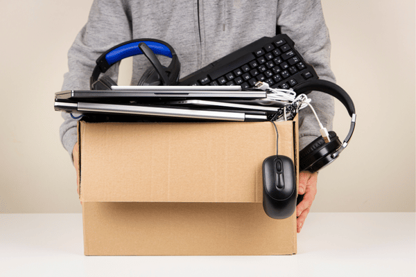 A person holding a cardboard box full of electronics