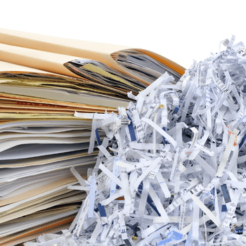 A stack file folders next to shredded paper